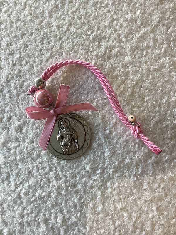 A silver medallion featuring Jesus Christ with a pink miniature Mati charm on top, attached to a pink cord with a rose-colored bead
